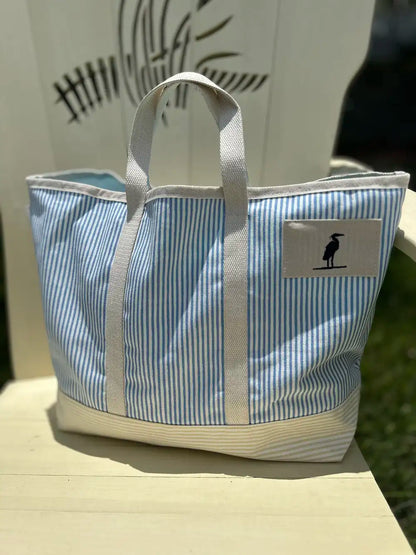 Tote Bag with heron icon stitched on the front.  The bag is pinstriped with a pretty blue on white.  The bag is made of canvas with sturdy straps. Eastern Shore Style. Boat tote bag, Beach tote bag, everyday bag. 